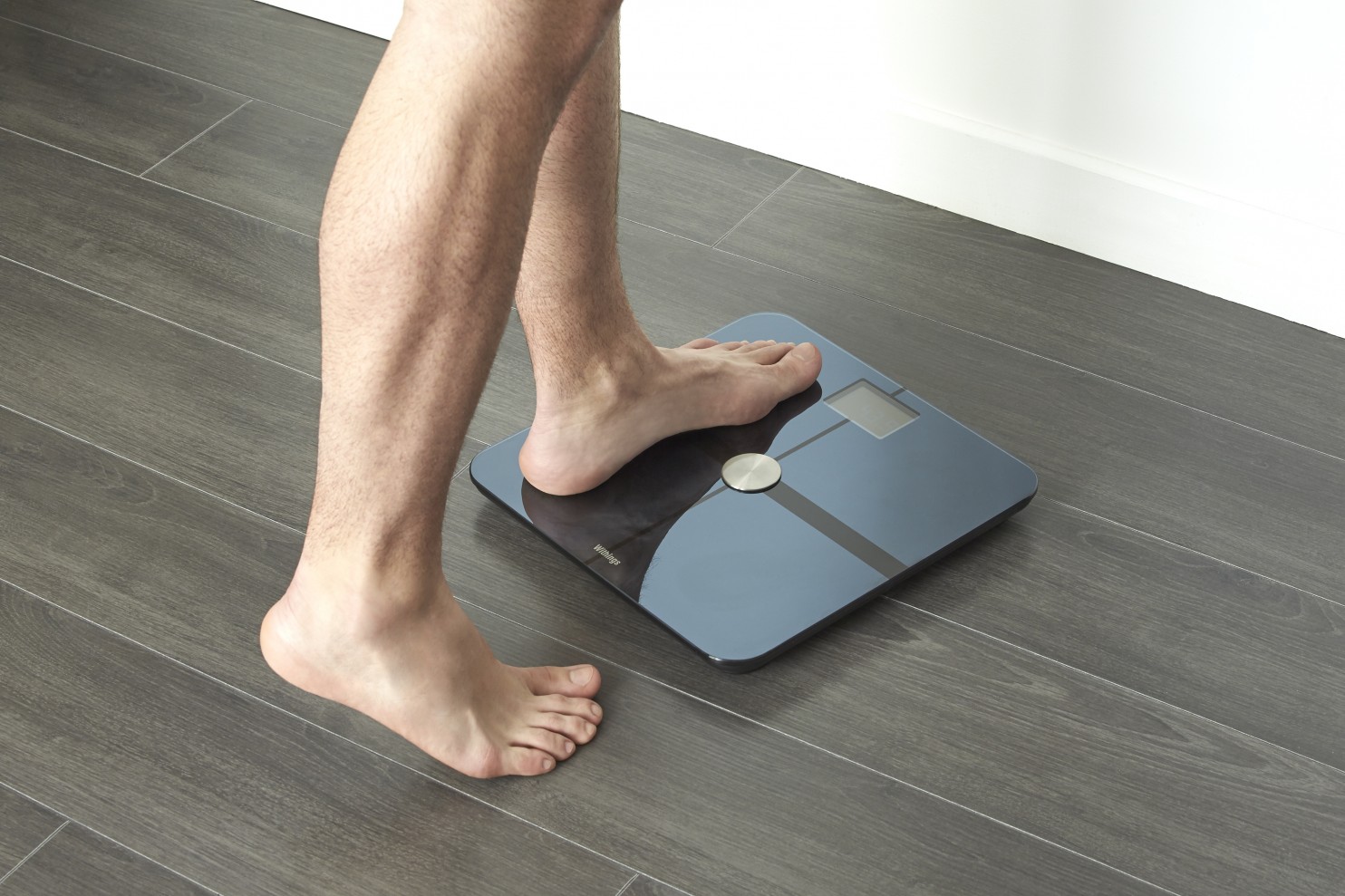 Image of a man stepping on a digital scale to measure weight