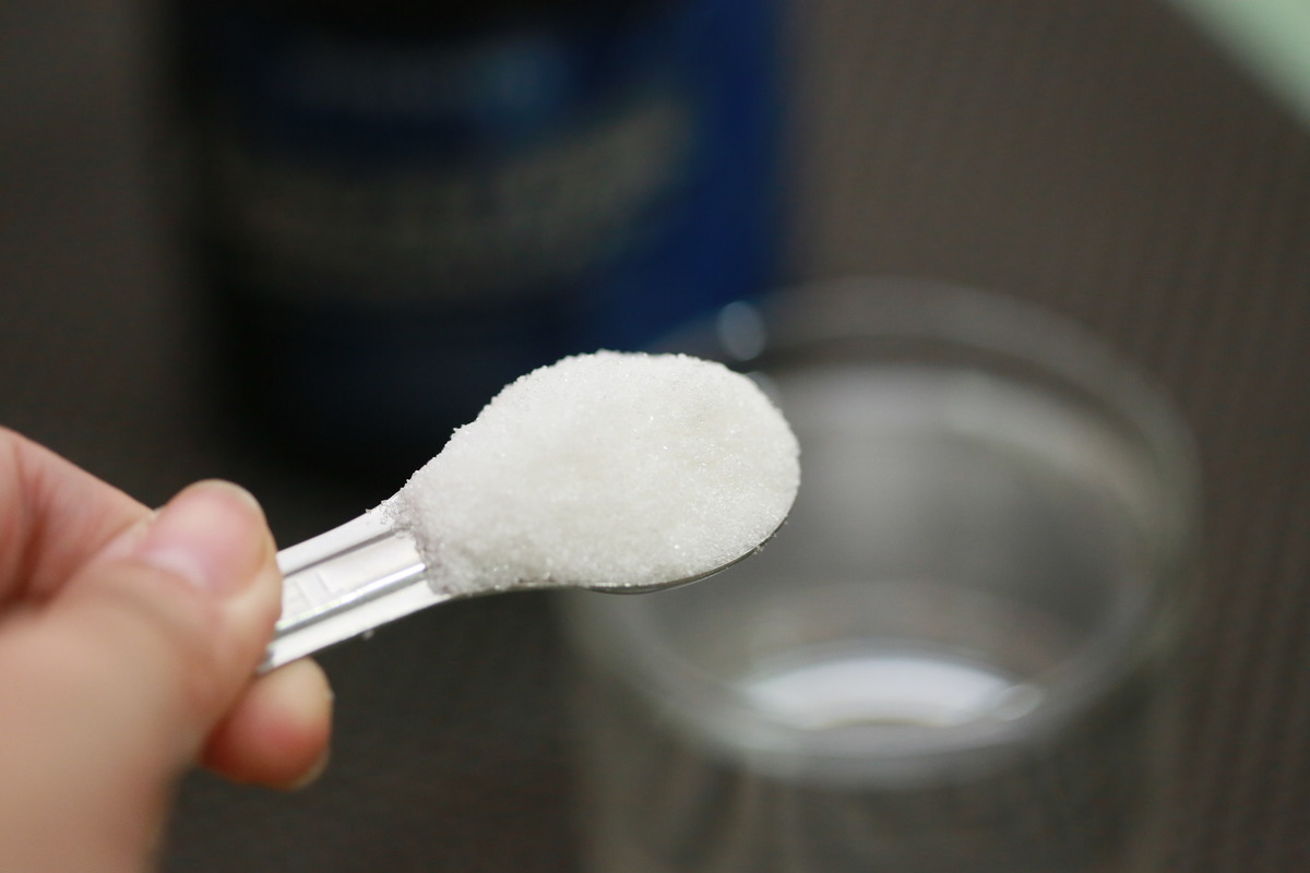Image of a scoop of creatine held above a bottle
