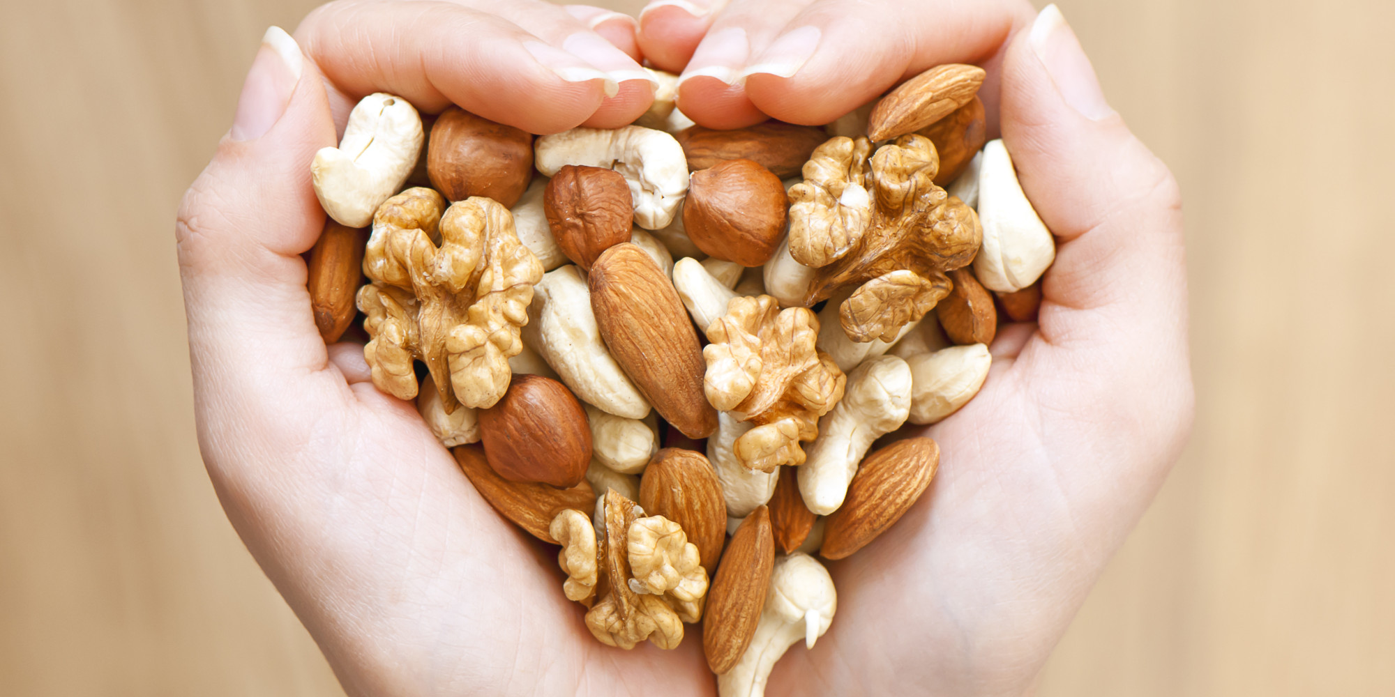 Image of a woman holding a handful of nuts in a heart shape