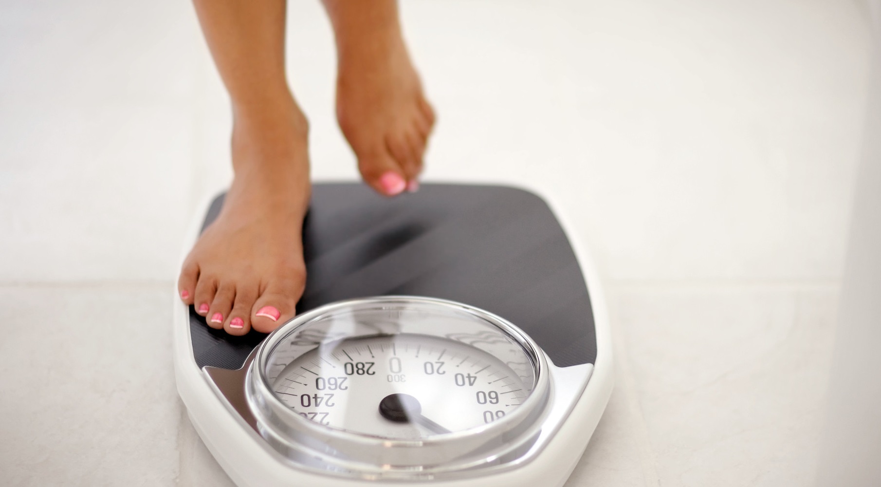Image of a woman stepping on a bathroom scale