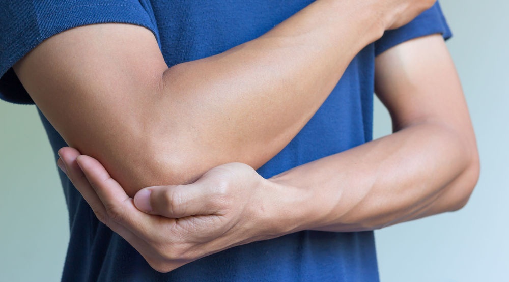 Image of a man holding his arm in pain from tendonitis